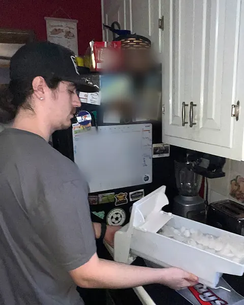Ethan sliding the ice bin out of a refrigerator freezer onto a protective mat
